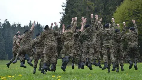 Ein Foto, das viele zufriedene Schweizer Soldaten beim Springen zeigt, nachdem sie ihre Abzeichen von RS Badge erhalten haben.